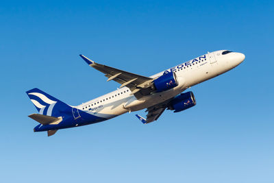 Low angle view of airplane flying against clear blue sky