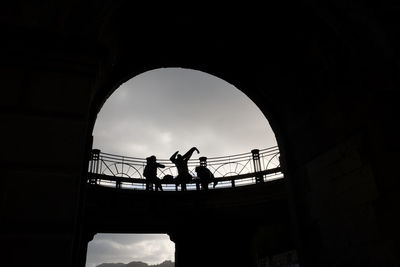 Low angle view of silhouette people on bridge against sky