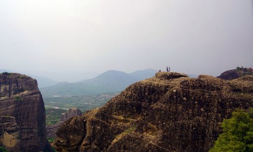 Panoramic view of people on cliff against sky