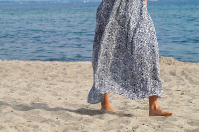 Low section of woman walking on sand at beach