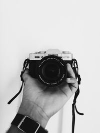 Close-up of hand holding camera over white background