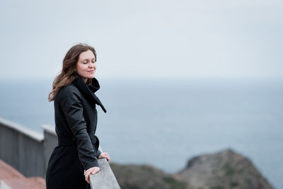 Young woman standing in sea against sky