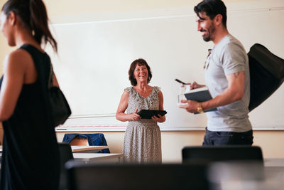 Senior woman smiling while holding digital tablet in classroom