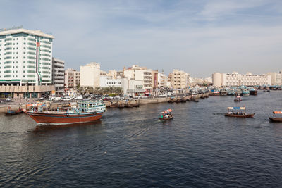 People on boat in river against city