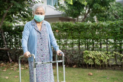 Senior woman wearing mask walking at lawn