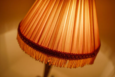 Close-up of illuminated lamp on table against wall