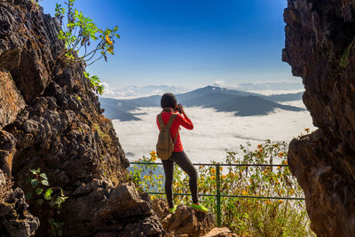 Woman photographing mountain against sky