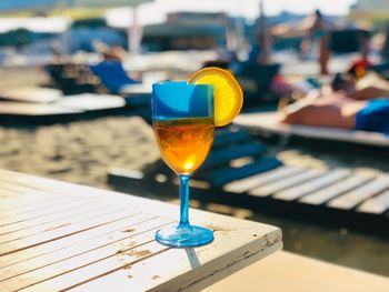 Glass of aperol spritz cocktail decorated with an orange slice placed on white table on the beach