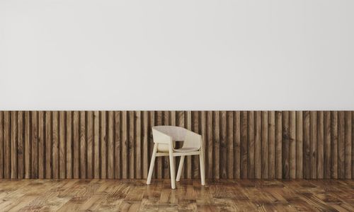 Wooden table and chairs on hardwood floor against wall