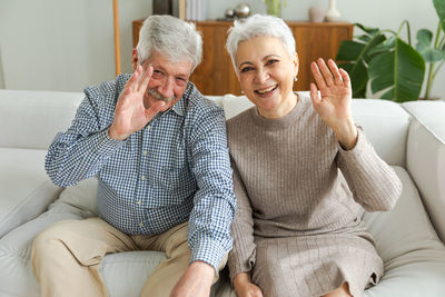 Portrait of smiling friends sitting on sofa at home