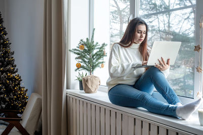 Portrait of young woman sitting on bed at home
