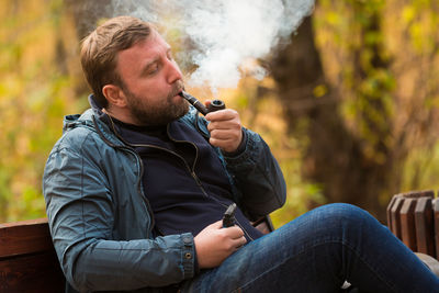 Man smoking pipe while sitting on bench