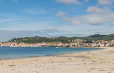 Scenic view of beach by city against sky