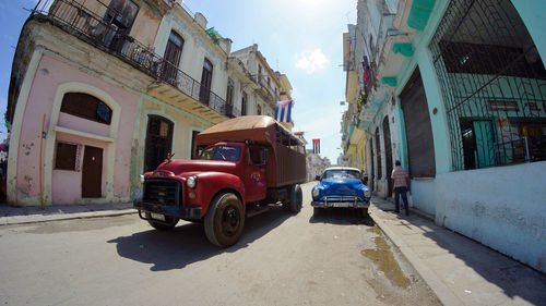 Cars on street by buildings against sky