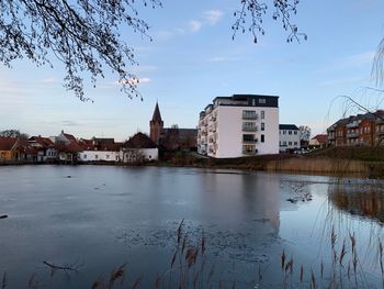 Buildings by river against sky in city