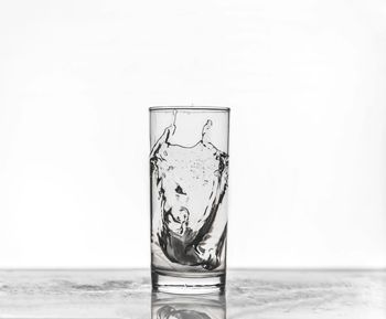 Close-up of glass over water against white background