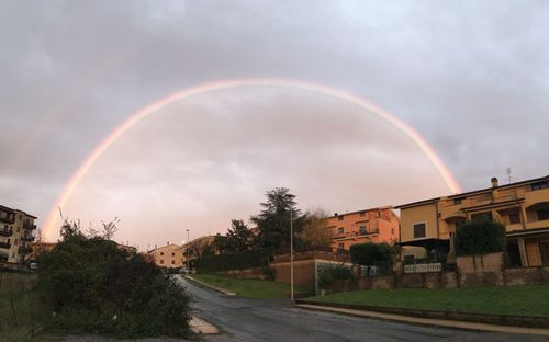Rainbow over buildings in city against sky