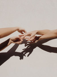 Cropped hands of people against gray wall