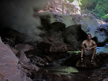 Shirtless man sitting in forest