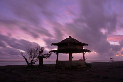 Traditional windmill on beach against sky at sunset