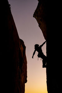 Beautiful view to silhouette of man climbing during sunset