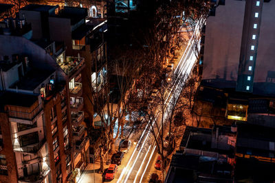 High angle view of illuminated light trail on street amidst buildings in city