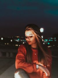 Young woman looking at illuminated city at night