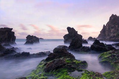 Scenic view of rocks in sea against sky during sunset