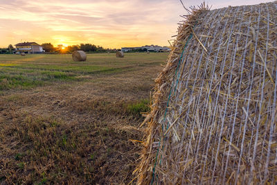 Hay bales on field against sky during sunset