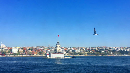 Buildings by sea against clear blue sky