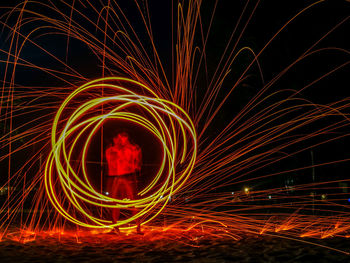 Man spinning illuminated wire wool at night