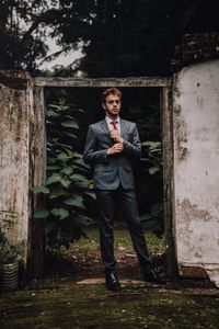 Portrait of young man standing against building