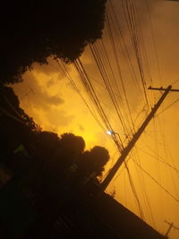 Silhouette trees and electricity pylon against sky during sunset