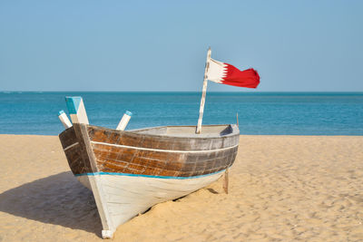 Rear view of woman sitting on beach against clear sky