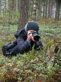 Woman photographing plant in forest