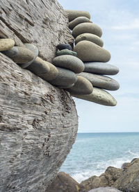 Stack of pebbles in sea against sky