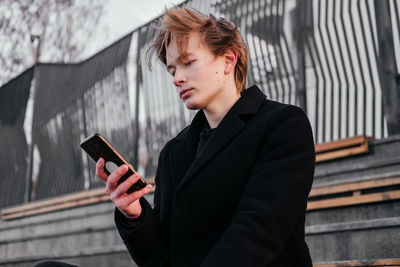 Young man using mobile phone outdoors