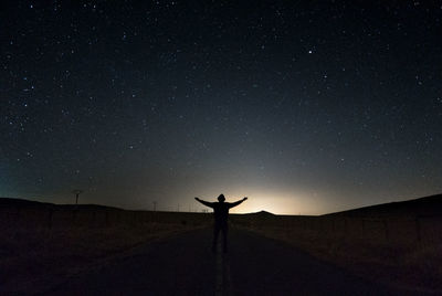 Silhouette man standing on road against sky at night