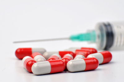 Close-up of capsules with syringe on white background