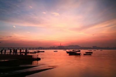 Boats in sea at sunset