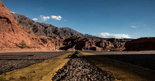 Surface level of road amidst rocks against sky