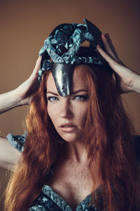 Portrait of young woman holding crown against colored background