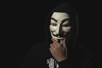Close-up of man wearing mask against black background