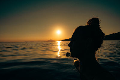 Silhouette woman standing at beach against sky during sunset