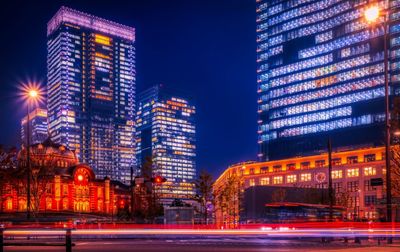 Light trails on road against illuminated buildings in city at night