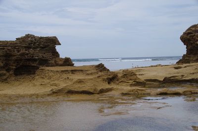 Rock formations on beach against sky