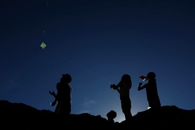 Low angle view of people against clear blue sky