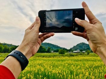 Midsection of man using mobile phone on field