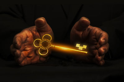 Close-up of man working on metal against black background