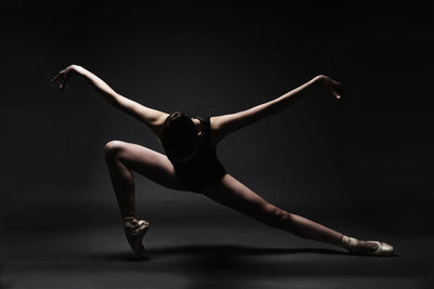 Ballet dancer dancing against gray background